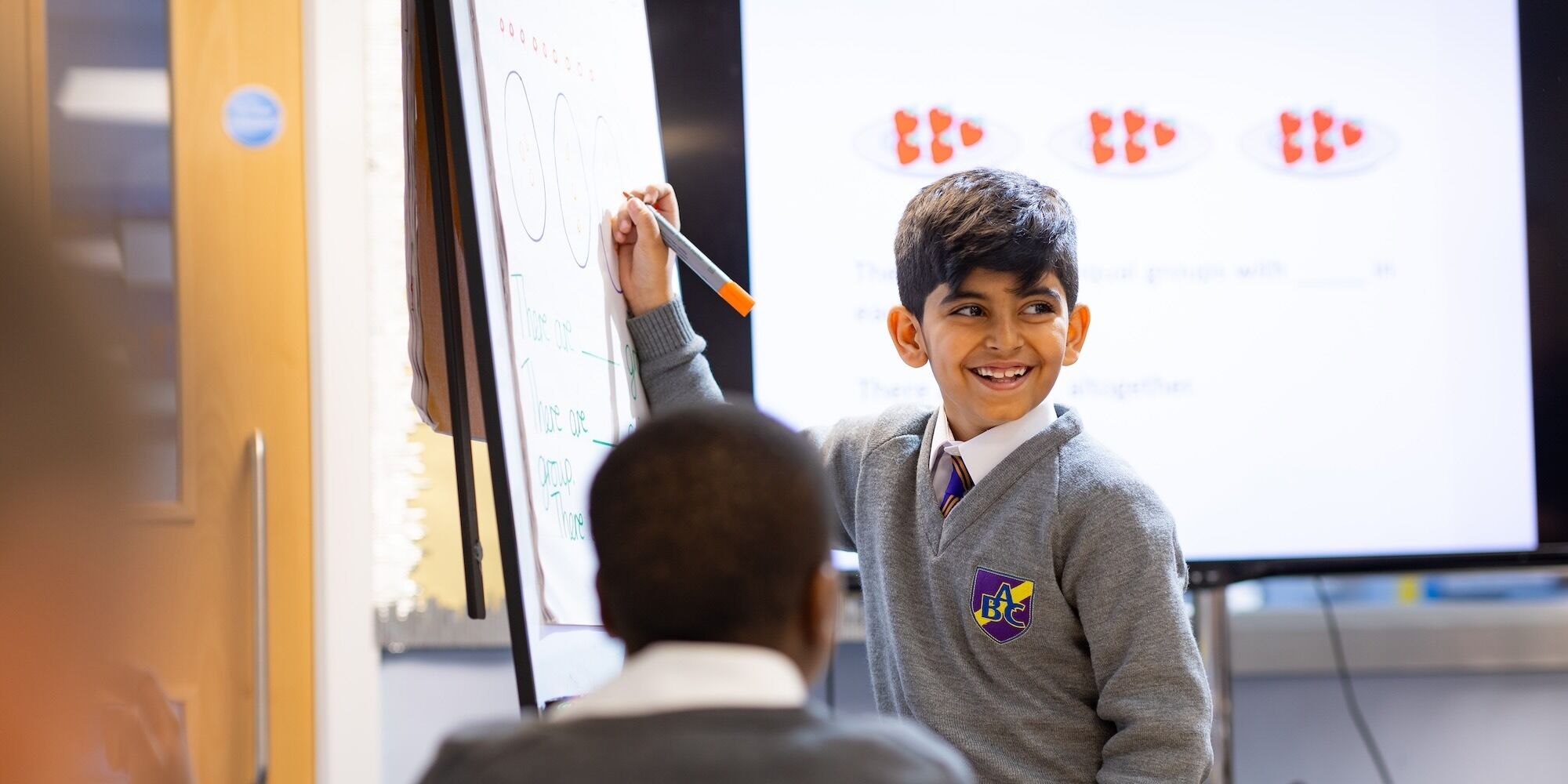 Belmont Castle Academy pupil writing on the whiteboard